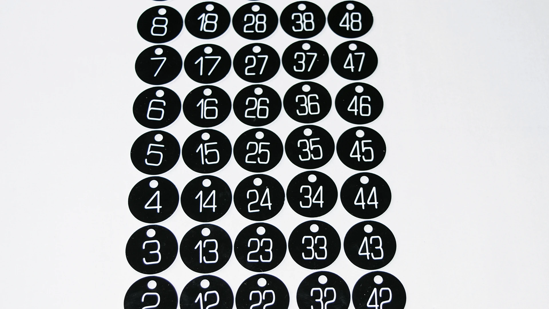 Black numbered asset identification discs arranged in a production set